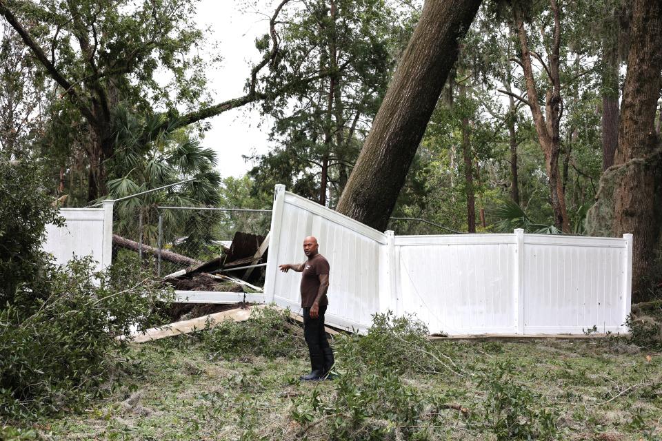 Angel Navarro points to his fence, pushed up by a toppled oak tree in the backyard of his home in Madison, Florida on Wednesday, Aug. 30, 2023, the day Hurricane Idalia hit Florida's Gulf Coast.