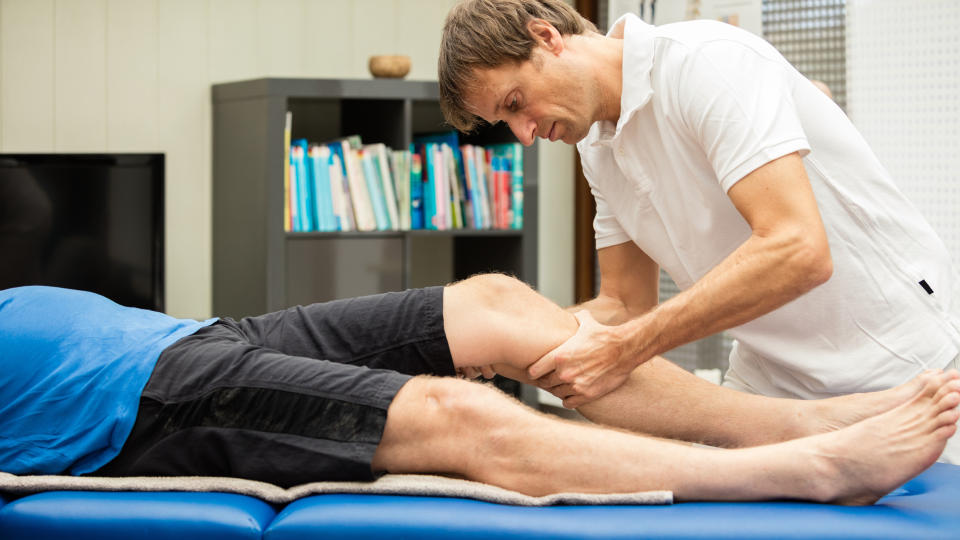 A man giving a sports massage to an athlete's calf muscles