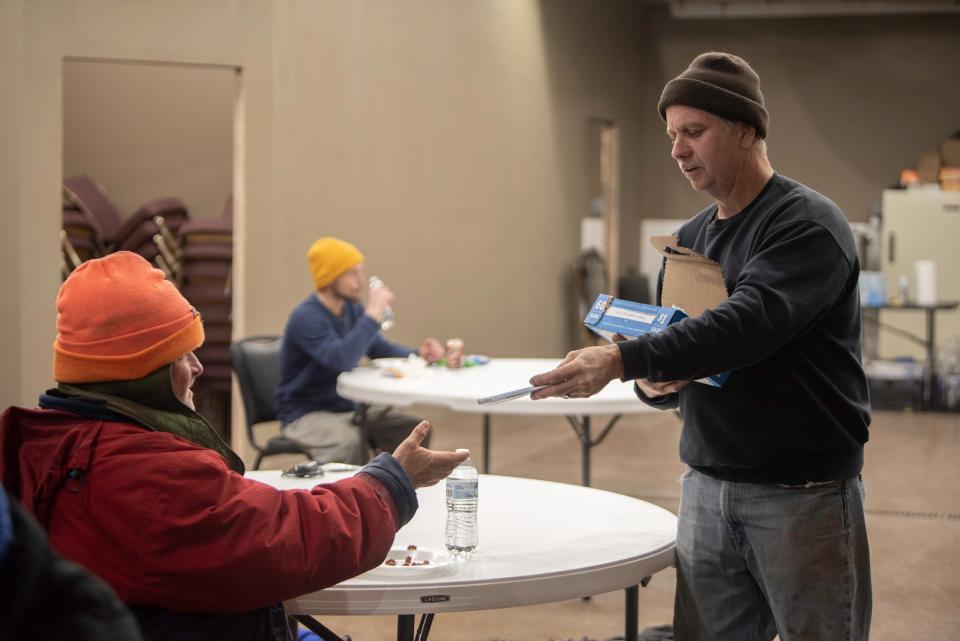 Crazy Faith Street Ministry's Lonny Kainz hands out candy bars to unhoused Puebloans at the nonprofit's overnight homeless shelter located at 3100 N. Elizabeth St. on Thursday, January 18, 2024.