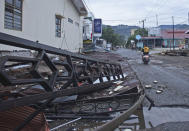 A motorist rides past a building damaged by an earthquake in Mamuju, West Sulawesi, Indonesia, Saturday, Jan. 16, 2021. Damaged roads and bridges, power blackouts and lack of heavy equipment on Saturday hampered Indonesia's rescuers after a strong and shallow earthquake left a number of people dead and injured on Sulawesi island. (AP Photo/Azhari Surahman)