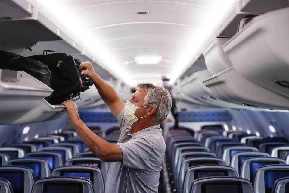 FILE - In this May 28, 2020, file photo, a passenger wears personal protective equipment on a Delta Airlines flight after landing in Minneapolis, United States of America. The European Union Aviation Safety Agency said Wednesday that from next week onward it is no longer recommending the use of medical masks at airports and on planes due to the coronavirus. (AP Photo/John Minchillo, File)