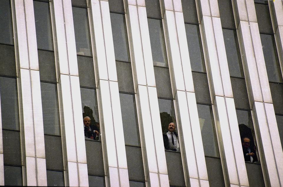 Workers peer through broken windows of the World Trade Center in New York, Feb. 26, 1993, after an explosion in an underground garage rocked the twin towers complex.  Heavy smoke, caused by underground fires, was reported throughout the buildings, causing the evacuation of the buildings.