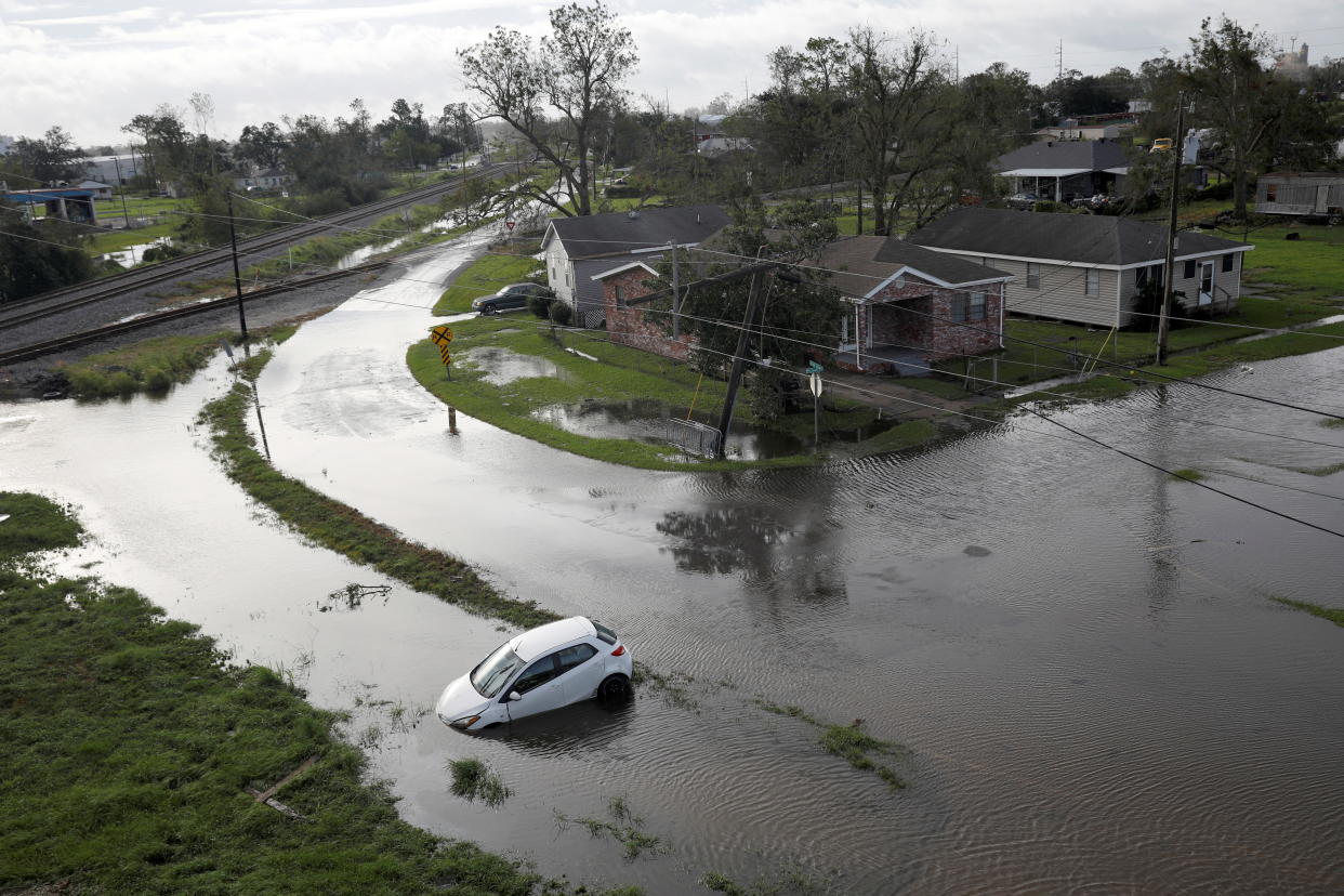 Flooded streets are seen from above with car partially submerged, nose down.