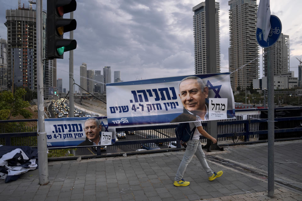 File - A man walks behind a Likud party election campaign banner depicting its leader, former Israeli Prime Minister Benjamin Netanyahu, in Tel Aviv, Israel, Thursday, Oct. 20, 2022. Israel is heading into its fifth election in under four years on Nov. 1. Hebrew on banner reads "Netanyahu, strong right wing for four years". (AP Photo/Oded Balilty, File)