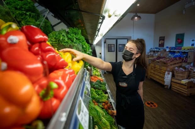 Brooklyn Marchand stocks vegetables at Hopcott Premium Meats in Pitt Meadows in August. A COVID-19 modelling expert in B.C. says the province should consider vaccinating essential workers before seniors as a more effective way to reduce virus transmission. (Ben Nelms/CBC - image credit)