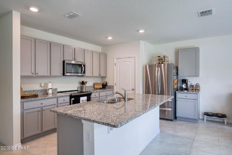 The modern open kitchen features a large center island, granite countertops, 36-inch cabinets and a large dining area.