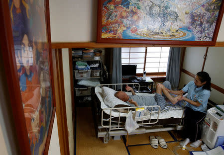 Mitsuru Niinuma, 69, who has terminal lung cancer, is massaged by a therapist in his room which was decorated with puzzles, put together by Niinuma's grandson in Tokyo, Japan, July 19, 2017. REUTERS/Kim Kyung-Hoon