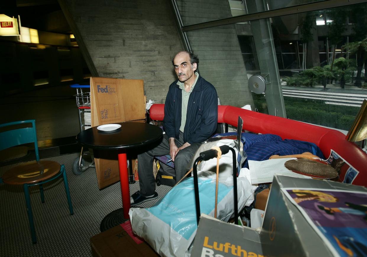 Mehran Karimi Nasseri sits among his belongings in a 2004 photograph taken at Charles de Gaulle Airport, where he lived for nearly 18 years. <a href="https://www.gettyimages.com/detail/news-photo/sir-alfred-mehran-59-years-old-originally-from-iran-has-news-photo/627630152?adppopup=true" rel="nofollow noopener" target="_blank" data-ylk="slk:Eric Fougere/VIP Images/Corbis via Getty Images;elm:context_link;itc:0;sec:content-canvas" class="link ">Eric Fougere/VIP Images/Corbis via Getty Images</a>