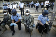 Philadelphia police and Pennsylvania National Guard take a knee at the suggestion of Philadelphia Police Deputy Commissioner Melvin Singleton, unseen, outside Philadelphia Police headquarters in Philadelphia, Monday, June 1, 2020 during a march calling for justice over the death of George Floyd, Floyd died after being restrained by Minneapolis police officers on May 25. (AP Photo/Matt Rourke)