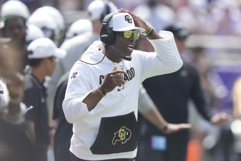 Colorado Deion Sanders touches his head as he looks on from the sideline.