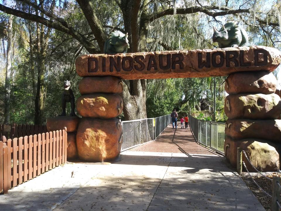 A family strolls past an archway at Dinosaur World in Plant City. The park features a 22,000-square-foot museum with animatronic dinosaurs, a 5,000-square-foot gift shop, playground area and courtyard with 25-foot-tall dinosaurs as well as a covered picnic area.