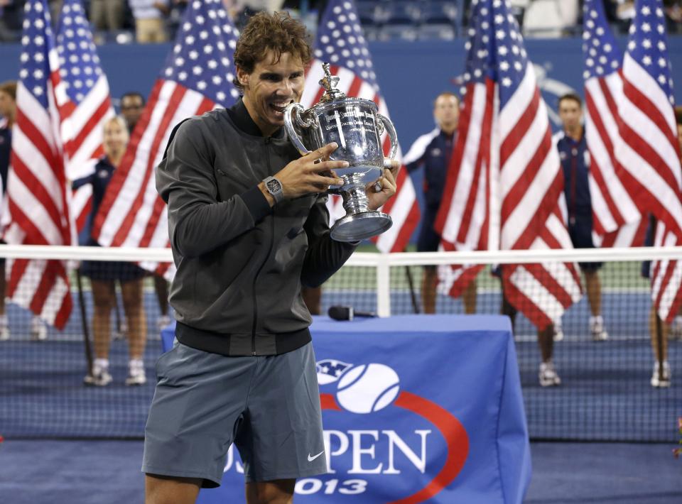 Rafael Nadal of Spain bites his trophy after defeating Novak Djokovic of Serbia in their men's final match at the U.S. Open tennis championships in New York, September 9, 2013. REUTERS/Mike Segar (UNITED STATES - Tags: SPORT TENNIS)
