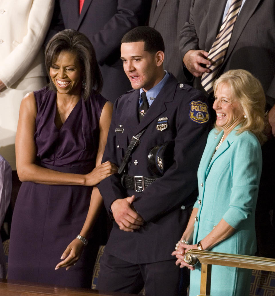 FILE - In this Tuesday, Feb. 24, 2009 file photo, first lady Michelle Obama and Jill Biden, wife of Vice President Joe Biden, stand with Philadelphia Police Officer Richard DeCoatsworth during President Barack Obama's address to a joint session of Congress in the House Chamber of the Capitol in Washington. The former Philadelphia police officer who was hailed as a hero will stand trial on charges he raped two prostitutes at gunpoint. The November trial comes after the 28-year-old DeCoatsworth withdrew a plea to reduced charges Tuesday, April 1, 2014. (AP Photo/Evan Vucci, File)