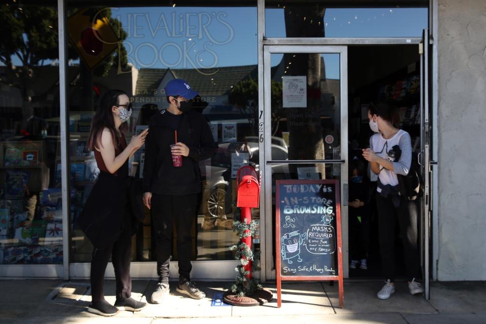 Customers wait outside a store with a sign advertising in-store browsing