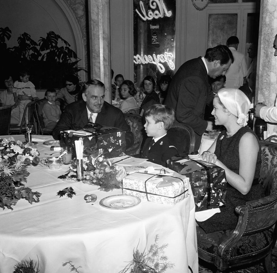 <p>The princess, Prince Rainier, and little Prince Albert celebrate Christmas at a party held by the Monegasque police force in 1965. She looks understatedly chic in a silk head scarf and simple LBD for the occasion.</p>