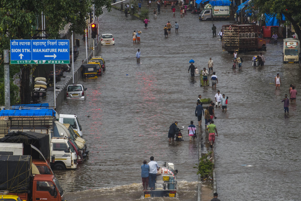 MUMBAI, INDIA - JULY 18: Commuters wade through a waterlogged road after heavy rain, at Sion, on July 18, 2021 in Mumbai, India. (Photo by Pratik Chorge/Hindustan Times via Getty Images)