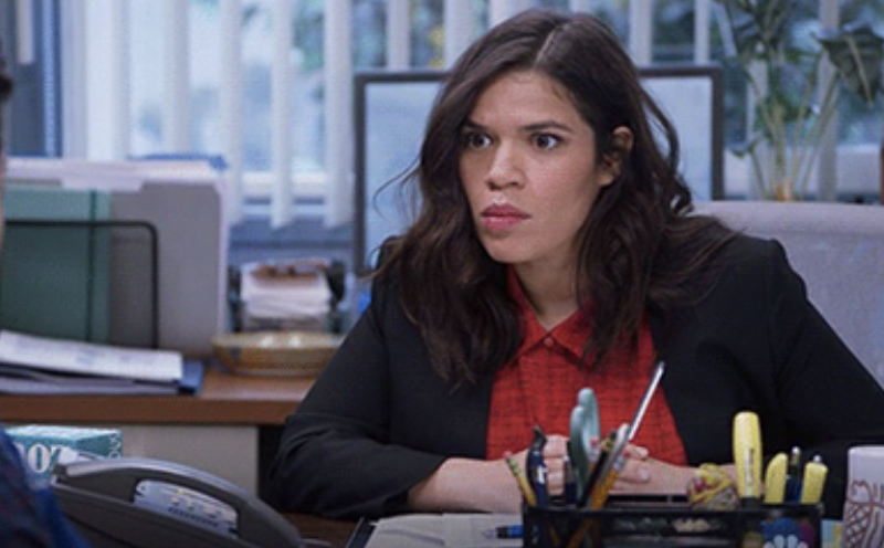 Woman in office setting, surprised expression, wearing a blazer over a top