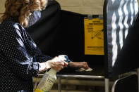FILE - In this Oct. 22, 2020, file photo, election clerk Cheryl Lupi sanitizes a voting booth inside Haverhill City Hall during early in-person voting in Haverhill, Mass. The United States is approaching a record for the number of new daily coronavirus cases in the latest ominous sign about the disease's grip on the nation. (AP Photo/Elise Amendola, File)