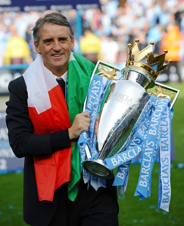 Roberto Mancini celebrates with Manchester City's Premier League trophy at The Etihad stadium on May 13, 2012. Last season's Premier League title was their first top-flight crown since 1968 and saw the manager rewarded with a new five-year deal