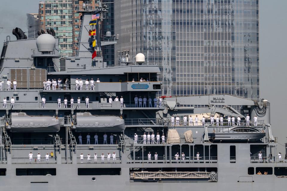 US Sailors and Marines stand on the flight deck of the USS Bataan, a Wasp-class amphibious assault ship, as it passes the Statue of Liberty during Fleet Week in New York Harbor on May 22, 2024.