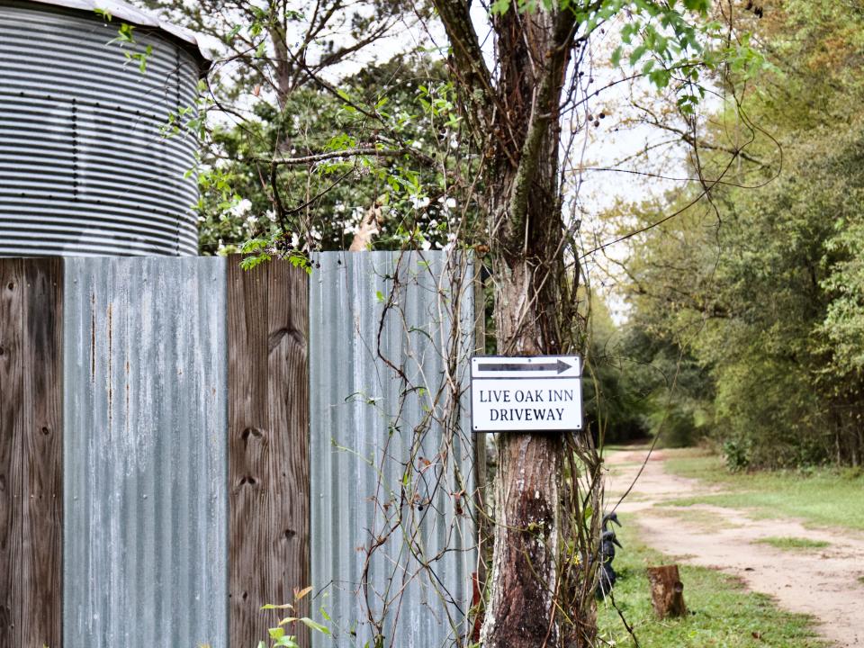 Metal privacy wall with a sign pointing to a driveway