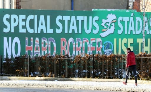 A pedestrian walks past a billboard in west Belfast on December 8, 2017 erected by Republican Party Sinn Fein calling for a special status for Northern Ireland with respect to Brexit and no hard borders in Ireland