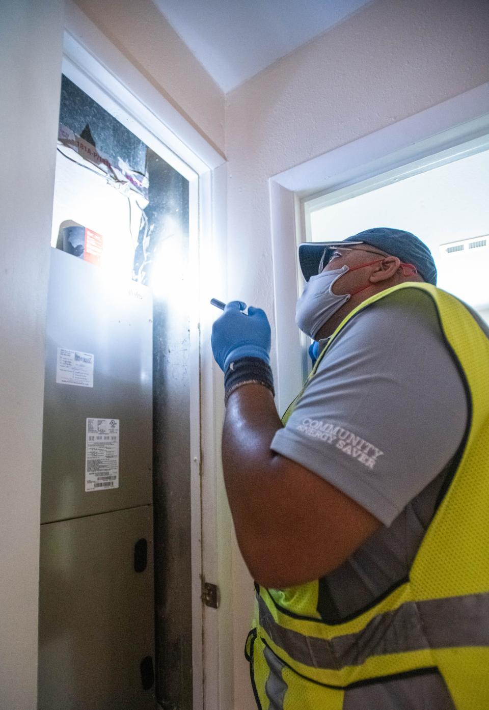 Larry Sanders with Honeywell inspects the heating and air conditioning system Thursday at Janis Jones' home as part of FPL's Community Energy Saver Program.