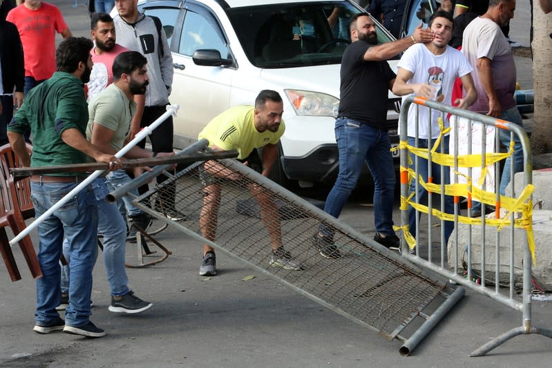 Men push a fence during tension between protesters and supporters of Lebanese Shi'ite groups Hezbollah and Amal at a roadblock on a main road in Beirut