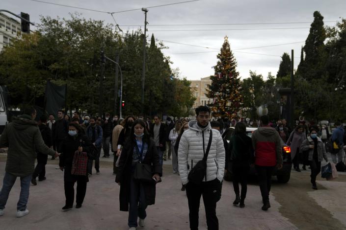 Pedestrians, some of them wearing face masks to protect against coronavirus, cross a road at Syntagma square in Athens, Greece, Monday, Nov. 29, 2021. Greece has recorded a spike in deaths and infections related to COVID-19 this month, amid heightened concerns in Europe due to the Omicron variant. The Greek government has ruling out the prospect of a general lockdown. (AP Photo/Thanassis Stavrakis)