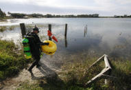 In this Saturday, Jan. 14, 2012 photo, Kenny Jenkins carries a float with a "Diver Down" flag as he prepares to place a geocache in about 33 ft. of water in Lake Denton in Avon Park Fla. Interest in geocaching has grown significantly over the years. But combining the two hobbies, geocaching and scuba diving, has only recently taken off. About 100 geocaches around the world today are only accessible with scuba gear, according to the geocaching.com database. (AP Photo/Wilfredo Lee)