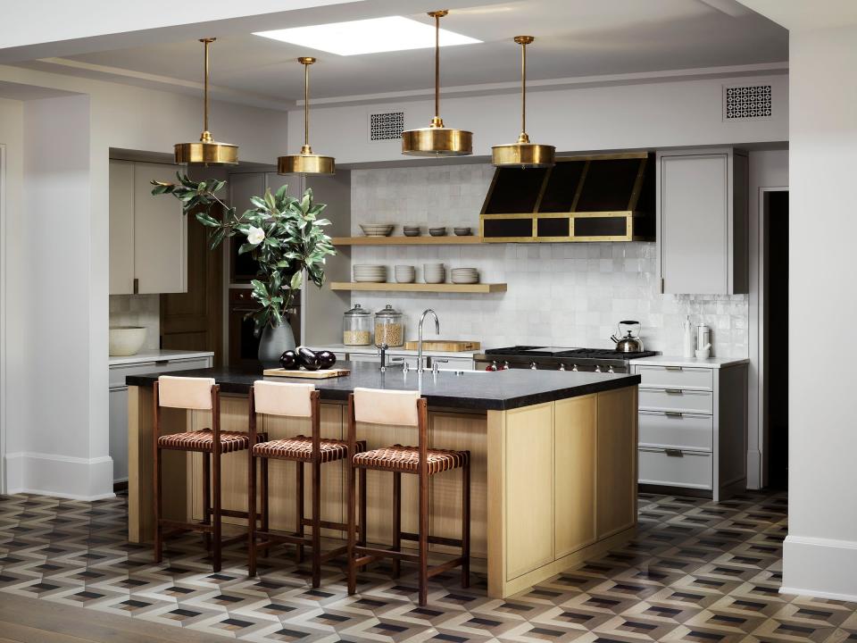 Patterned parquet floors, designed by Studio Seiders and fabricated by Kristynik Hardwood Flooring, add a visual punch to the clean-lined and light-hued open kitchen. The burnished brass pendants are from Roman and Williams Guild.
