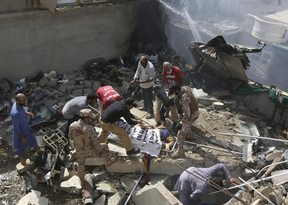 Volunteers cover the dead body of a plane crash victim at the site of the crash in Karachi, Pakistan, Friday, May 22, 2020. An aviation official says a passenger plane belonging to state-run Pakistan International Airlines carrying more than 100 passengers and crew has crashed near the southern port city of Karachi. There were no immediate reports on the number of casualties. (AP Photo/Fareed Khan)