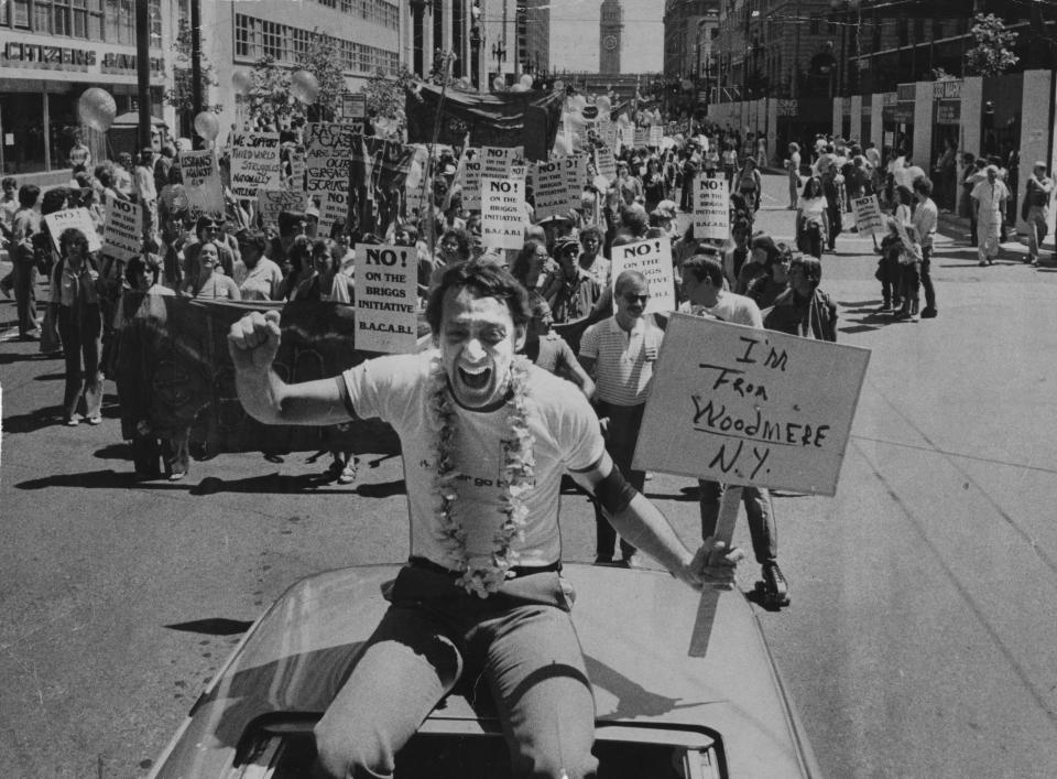 Harvey Milk at the Gay Pride Parade carrying a side reading, “I'm from Woodmere, New York”