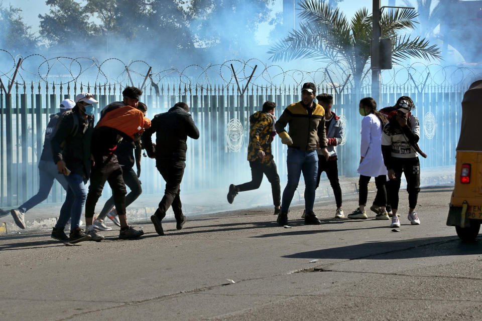 Anti-government protesters run as security forces fire tear gas to disperse them during a clashe in Baghdad, Iraq, Sunday, Jan. 26, 2020. (AP Photo/Hadi Mizban)