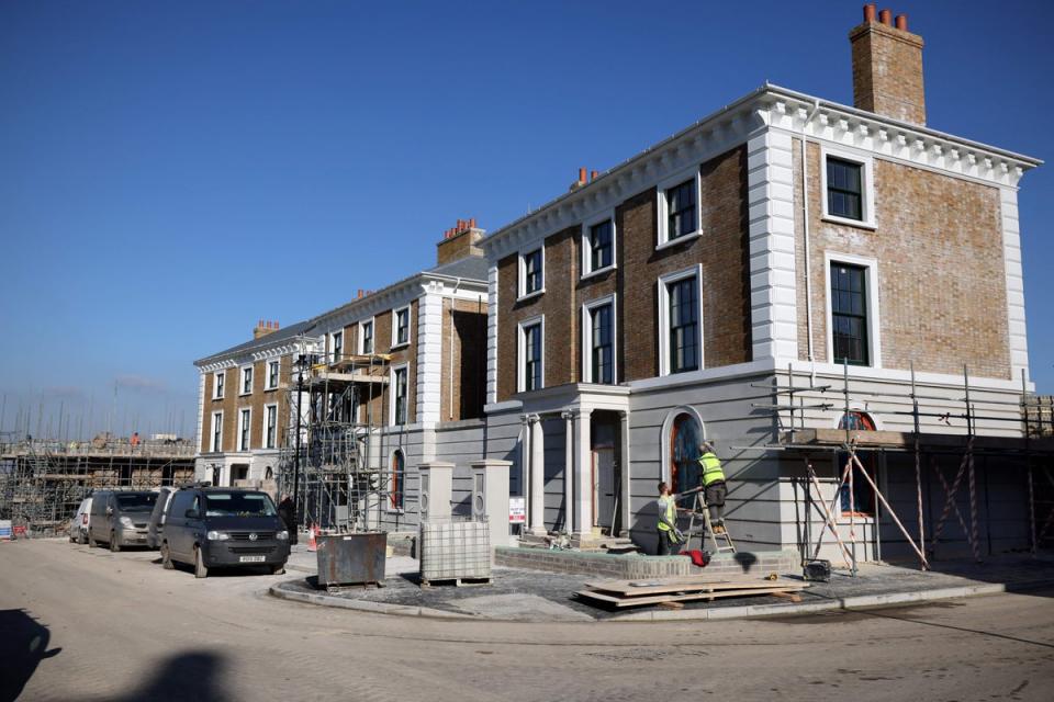 Construction builders work on the facade of a newly built house in the latest phase of development in Poundbury (AFP via Getty Images)