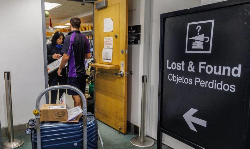 Terminal Operations specialist Miriam Marroquin, hands out items been shipped via Fedex to Emilio Falcon, after owners claimed them at the Lost and Found department at Miami International Airport, on Tuesday December 13, 2023.