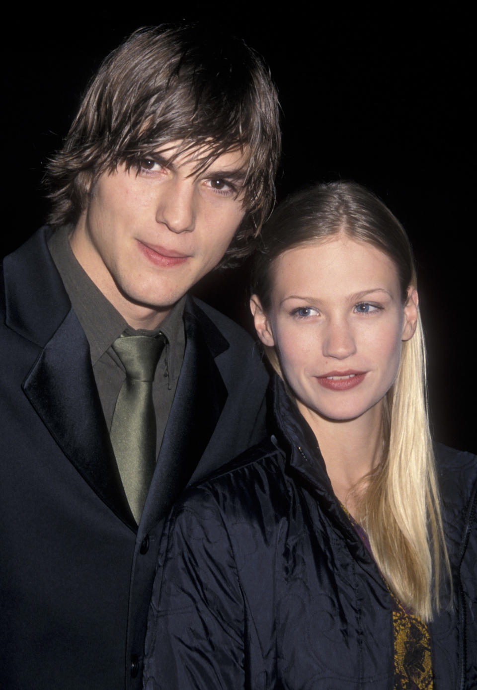 Ashton Kutcher with a shaggy haircut and dark suit, and tie standing next to January Jones who's wearing a dark jacket at the premiere of Reindeer Games