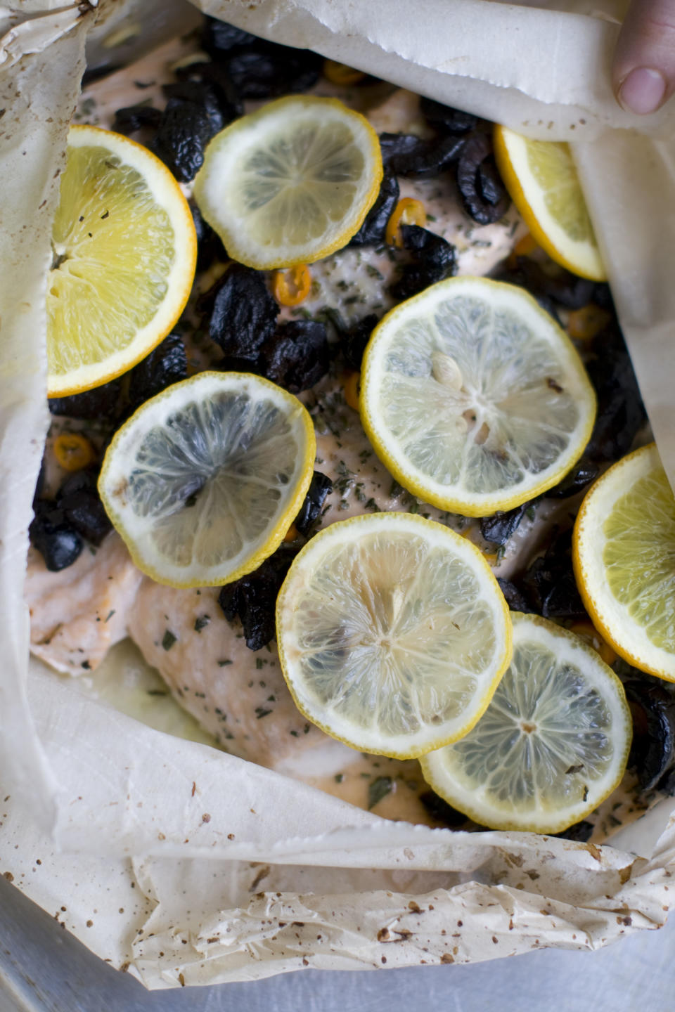 This Dec. 2, 2013 photo shows salmon baked in a bag with citrus, olive and chilies in Concord, N.H. The bag keeps the flavor and moisture trapped inside during cooking, allowing the juices from the fish and the other ingredients to mingle and become a wonderful sauce. (AP Photo/Matthew Mead)