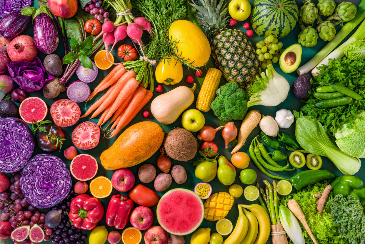 Colorful raw fruits and vegetables varied vegan food, vivid rainbow arrangement full frame background