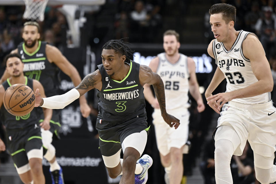 Minnesota Timberwolves' Jaden McDaniels (3) and San Antonio Spurs' Zach Collins chase the ball during the first half of an NBA basketball game, Sunday, Oct. 30, 2022, in San Antonio. (AP Photo/Darren Abate)