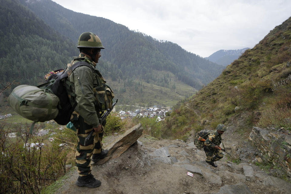 A man carries electronic voting machines as election officials walk to a polling booth in a remote mountain area on the eve of the first round of voting in the six-week long national election at Dessa village in Doda district, Jammu and Kashmir, India, April 18, 2024. (AP Photo/Channi Anand)