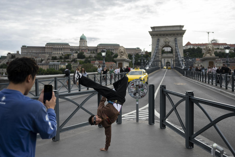 Tourists pose for a photo, with the newly renovated Chain Bridge and Buda Castle in the background on Wednesday, Aug. 9, 2023. Budapest hosts the World Athletics Championships from 19-27 August 2023. (AP Photo/Denes Erdos)
