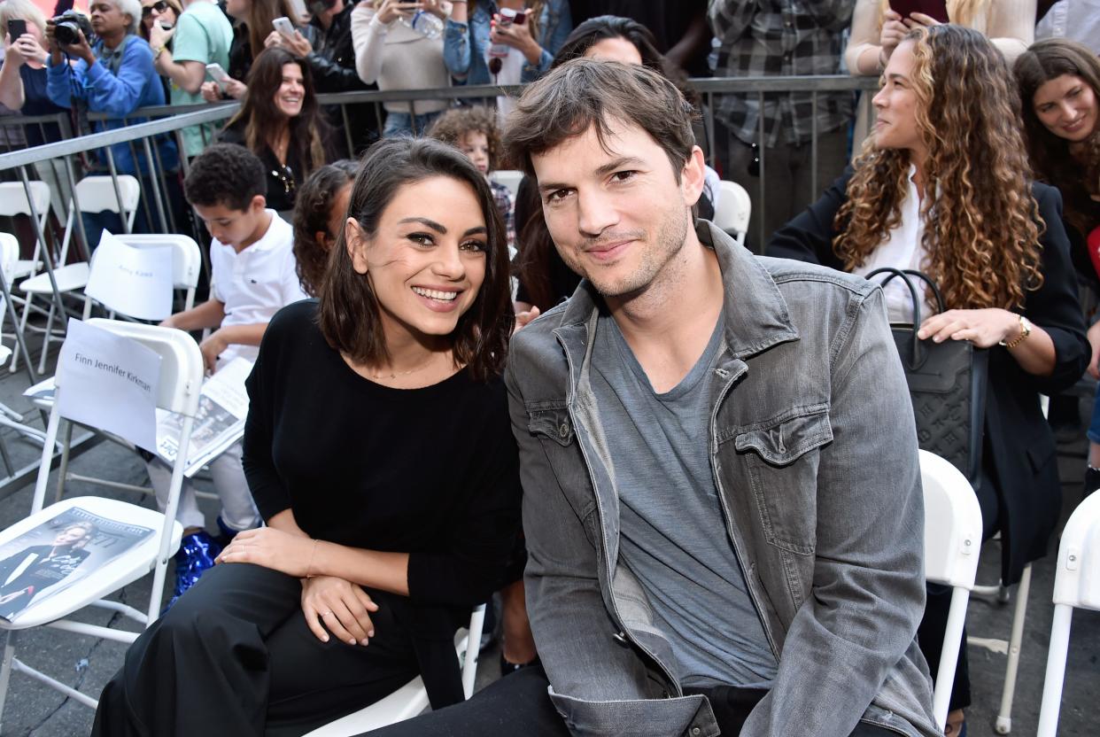 Mila Kunis and Ashton Kutcher leaning toward each other and smiling.