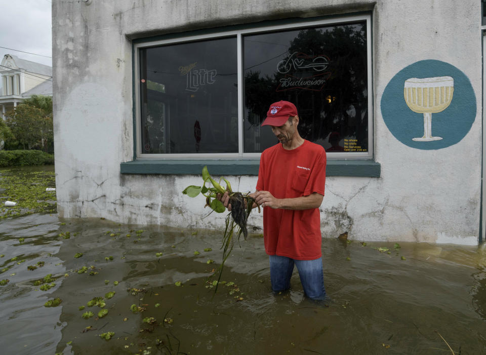 Cilton Bordelon picks up a plant washed into shore as he wades through storm surge from Lake Pontchartrain on Lakeshore Drive in Mandeville, La., as Hurricane Barry approaches  Saturday, July 13, 2019.  Barry had strengthened into a Category 1 hurricane by Saturday morning, with maximum sustained winds of 75 mph (120 kph), the National Hurricane Center said.  (AP Photo/Matthew Hinton)