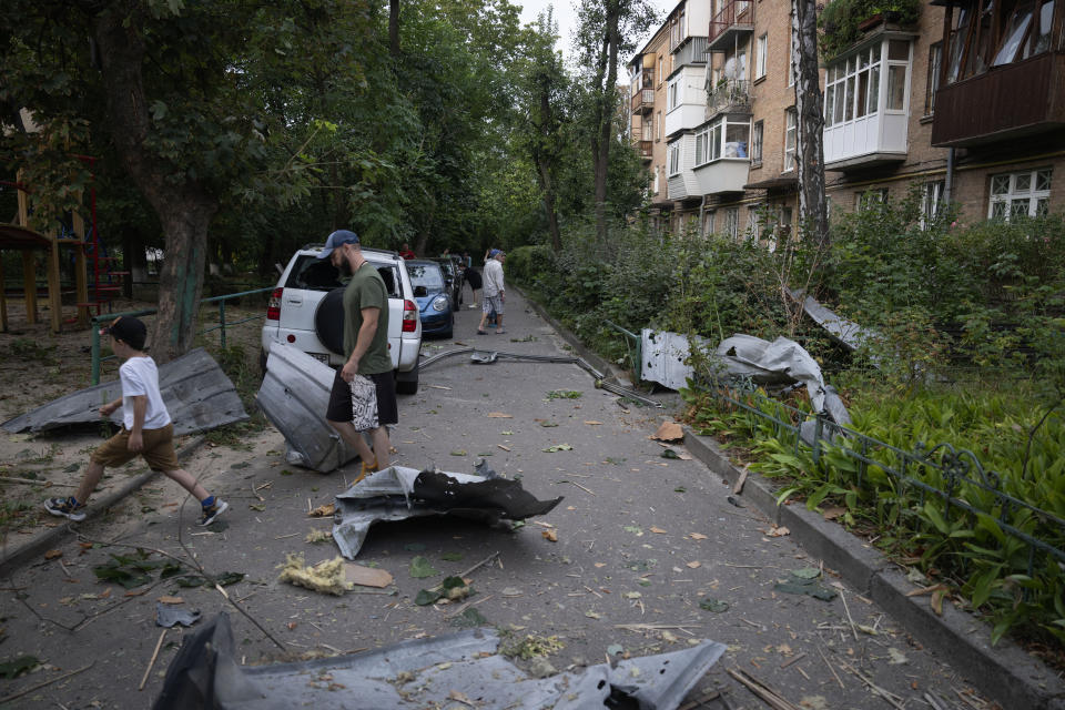 Local residents pass by debris that fell down from their damaged house after a Russian rocket attack in Kyiv, Ukraine, Wednesday, Aug. 30, 2023. (AP Photo/Efrem Lukatsky)