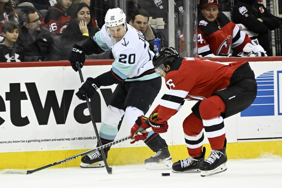 New Jersey Devils defenseman John Marino (6) checks Seattle Kraken right wing Eeli Tolvanen (20) during the first period of an NHL hockey game Thursday, Feb. 9, 2023, in Newark, N.J. (AP Photo/Bill Kostroun)