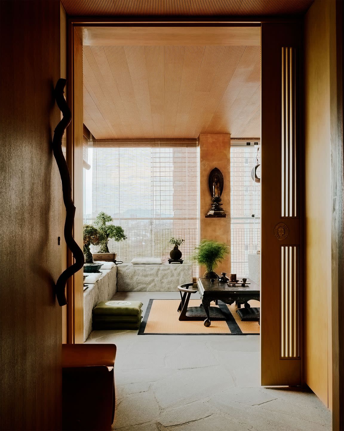 a foyer leading to the living room has a sliding wood door, stone floor, another door with a larged curved vine serving as a door handle