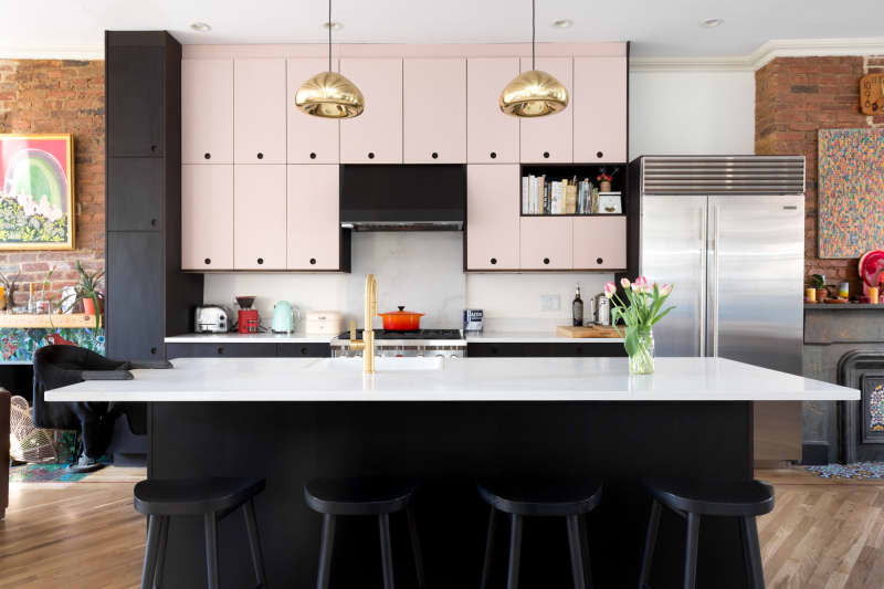 A kitchen with white upper cabinets and countertops as well as black hardware and lower cabinets