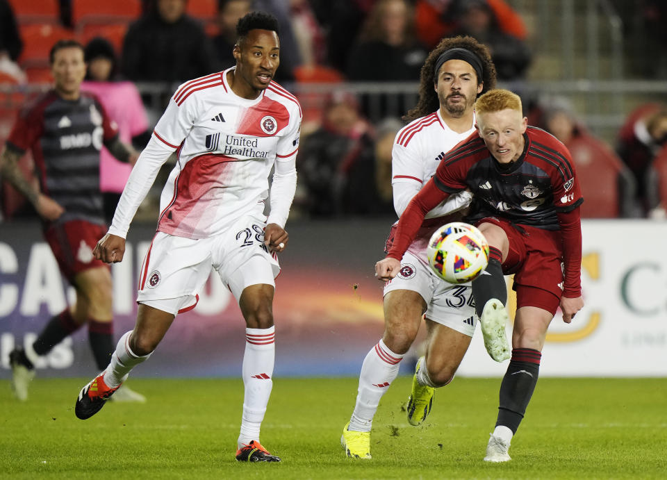 Toronto FC's Matty Longstaff, front right, moves the ball as New England Revolution's Mark-Anthony Kaye (28) and Ryan Spaulding (34) defend during second-half MLS soccer match action in Toronto, Saturday, April 20, 2024. (Frank Gunn/The Canadian Press via AP)