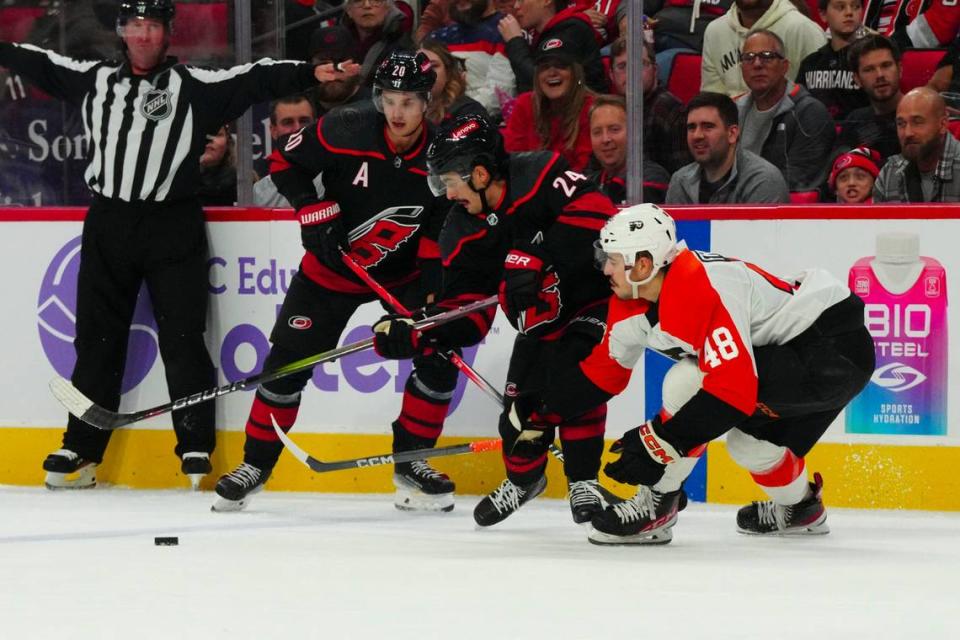 Nov 15, 2023; Raleigh, North Carolina, USA; Carolina Hurricanes center Seth Jarvis (24) and center Sebastian Aho (20) try to control the puck against Philadelphia Flyers center Morgan Frost (48) during the first period at PNC Arena. Mandatory Credit: James Guillory-USA TODAY Sports
